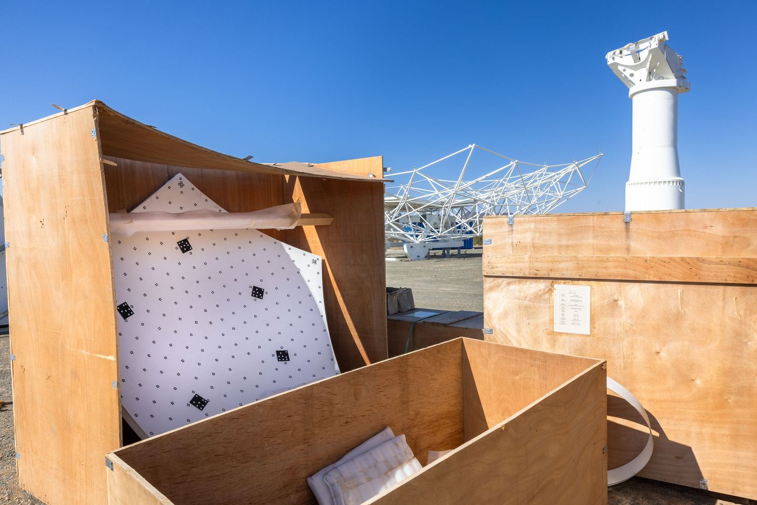 Desert facility with white domes and tan-colored building structures against blue sky.