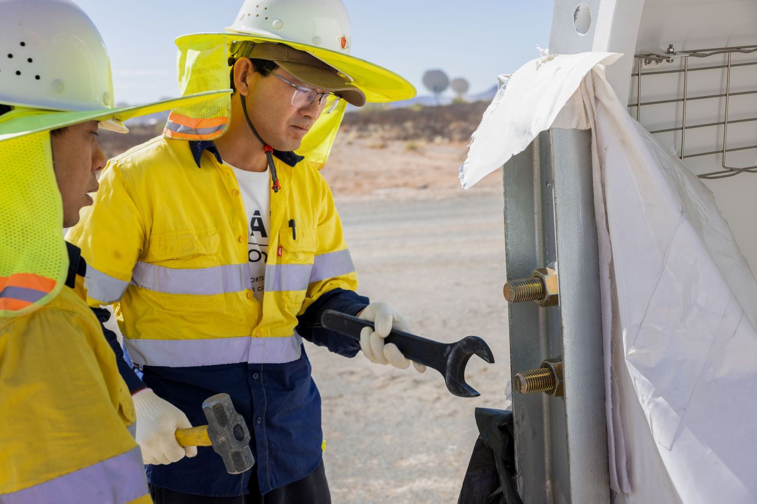 Workers in high-visibility gear perform maintenance tasks at industrial site.
