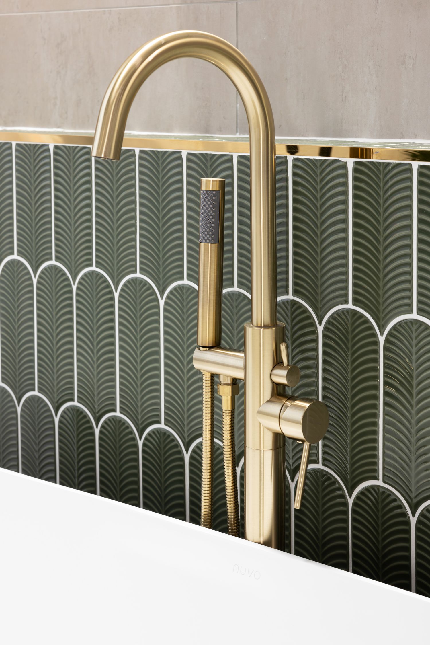 Gold faucet fixture against green art deco tile backsplash with fan pattern.
