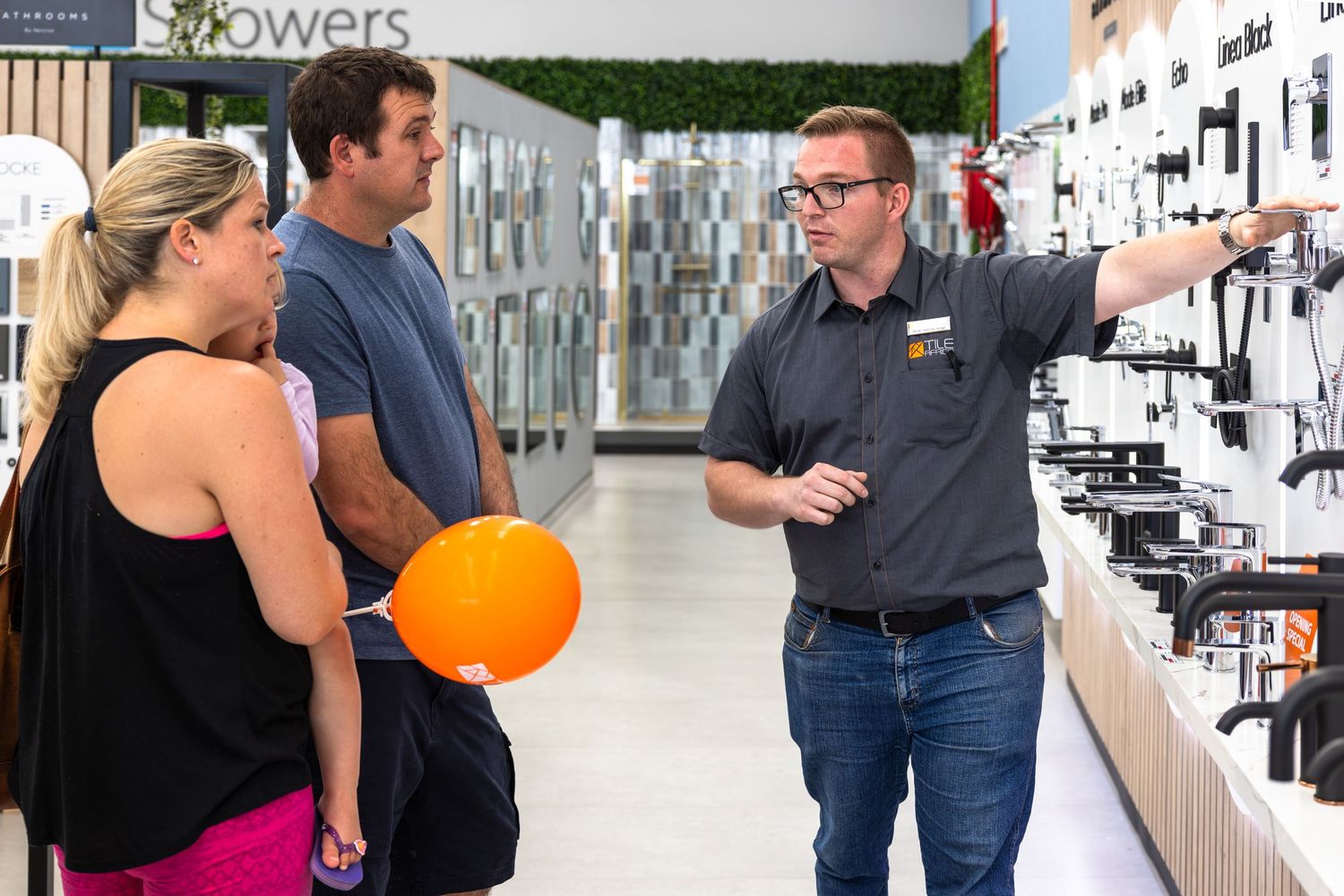 People mingling in a retail space with display walls and orange balloons.