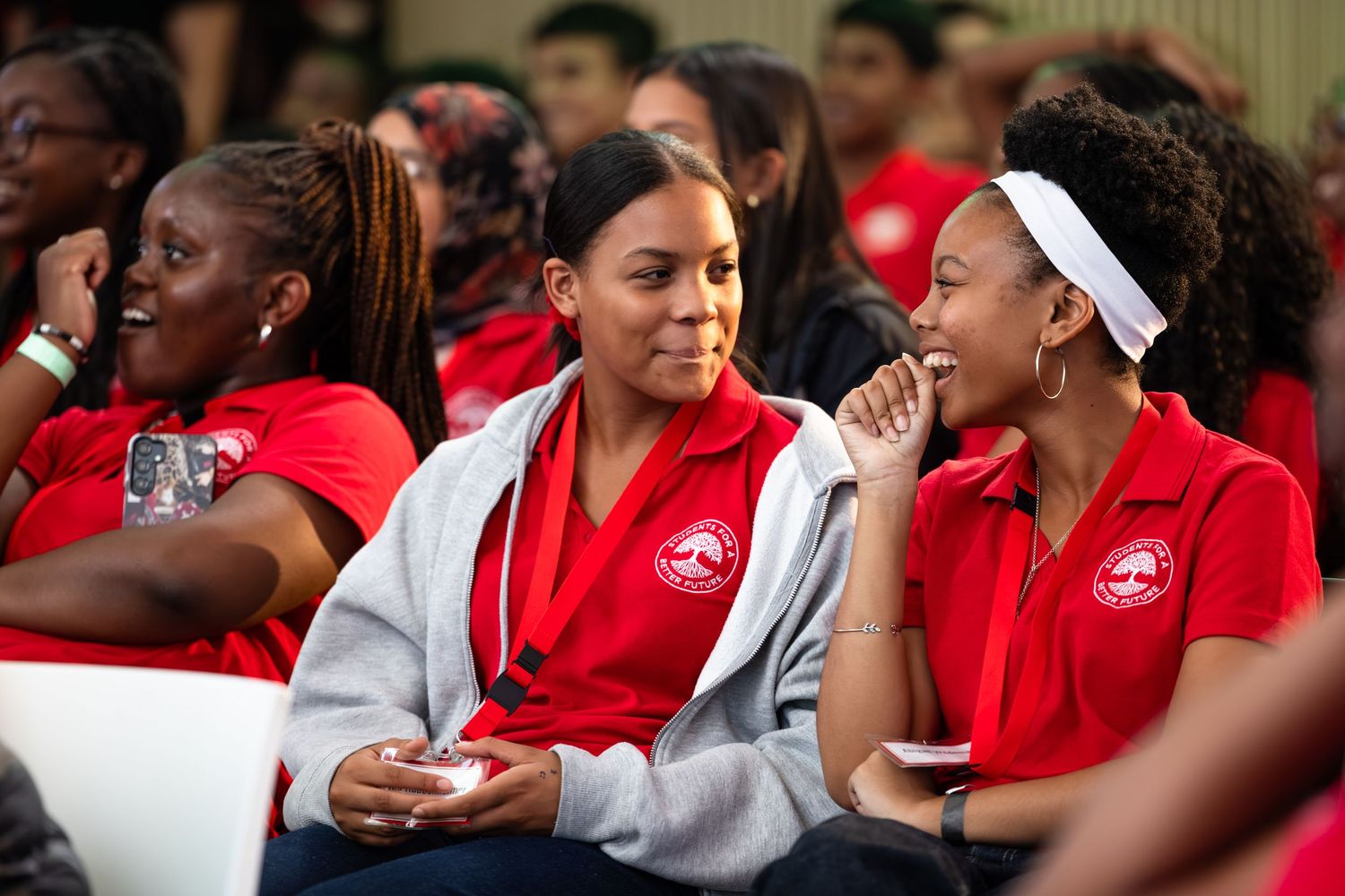 A group in red uniforms sits together at an event engaging in animated conversation.