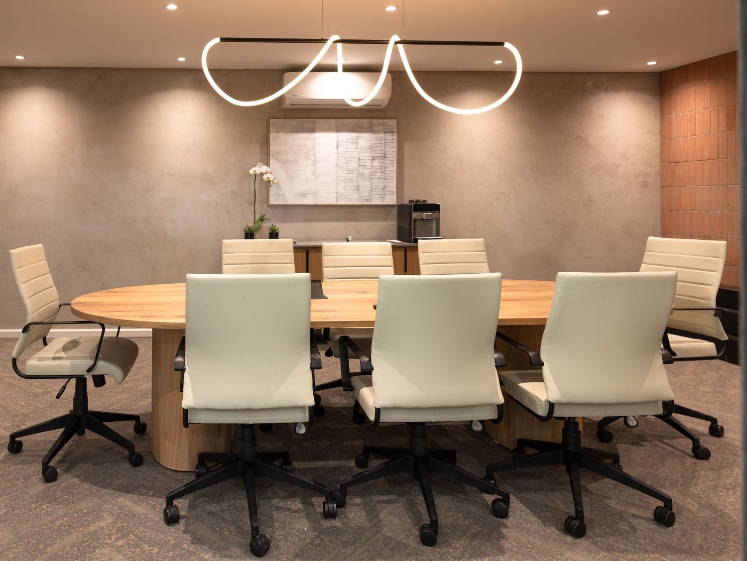 Modern conference room with ergonomic chairs and wooden table in neutral tones.