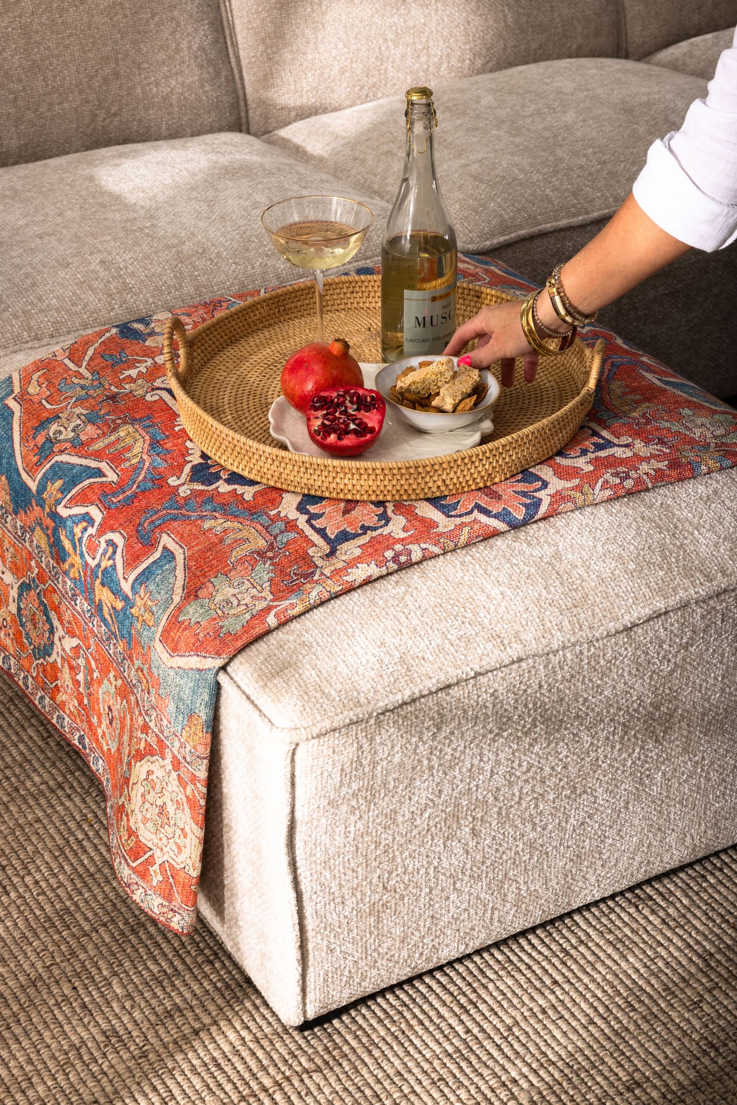 A colorfully patterned fabric is being arranged on a beige couch or ottoman in a series of progressive shots.