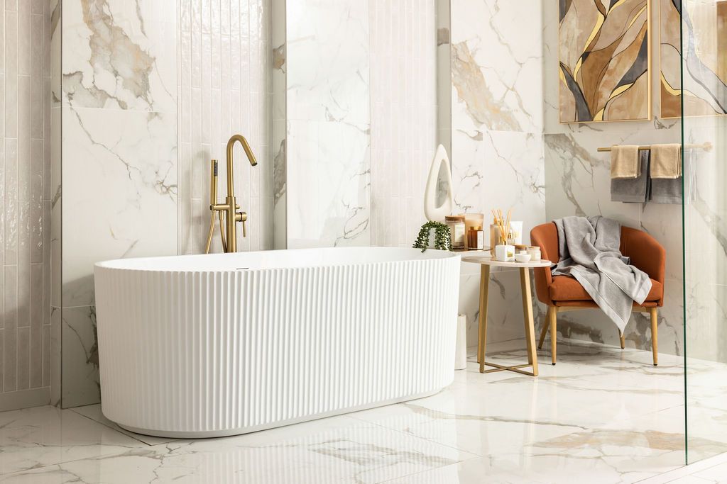 Luxurious marble bathroom interior with freestanding tub, gold fixtures, and natural light streaming through windows.