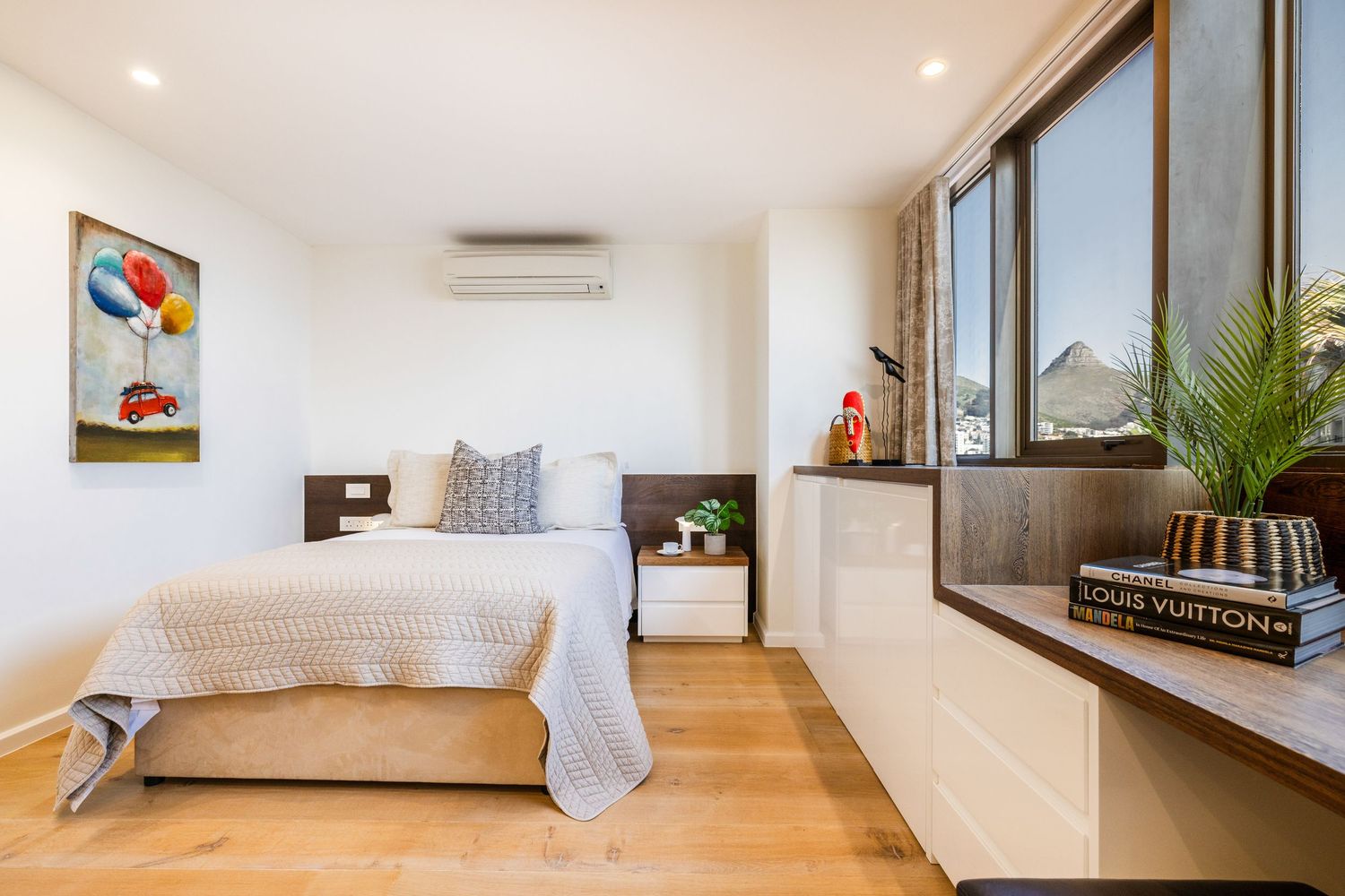 Bright white bedroom interior with hardwood floors and large windows showing multiple angles.