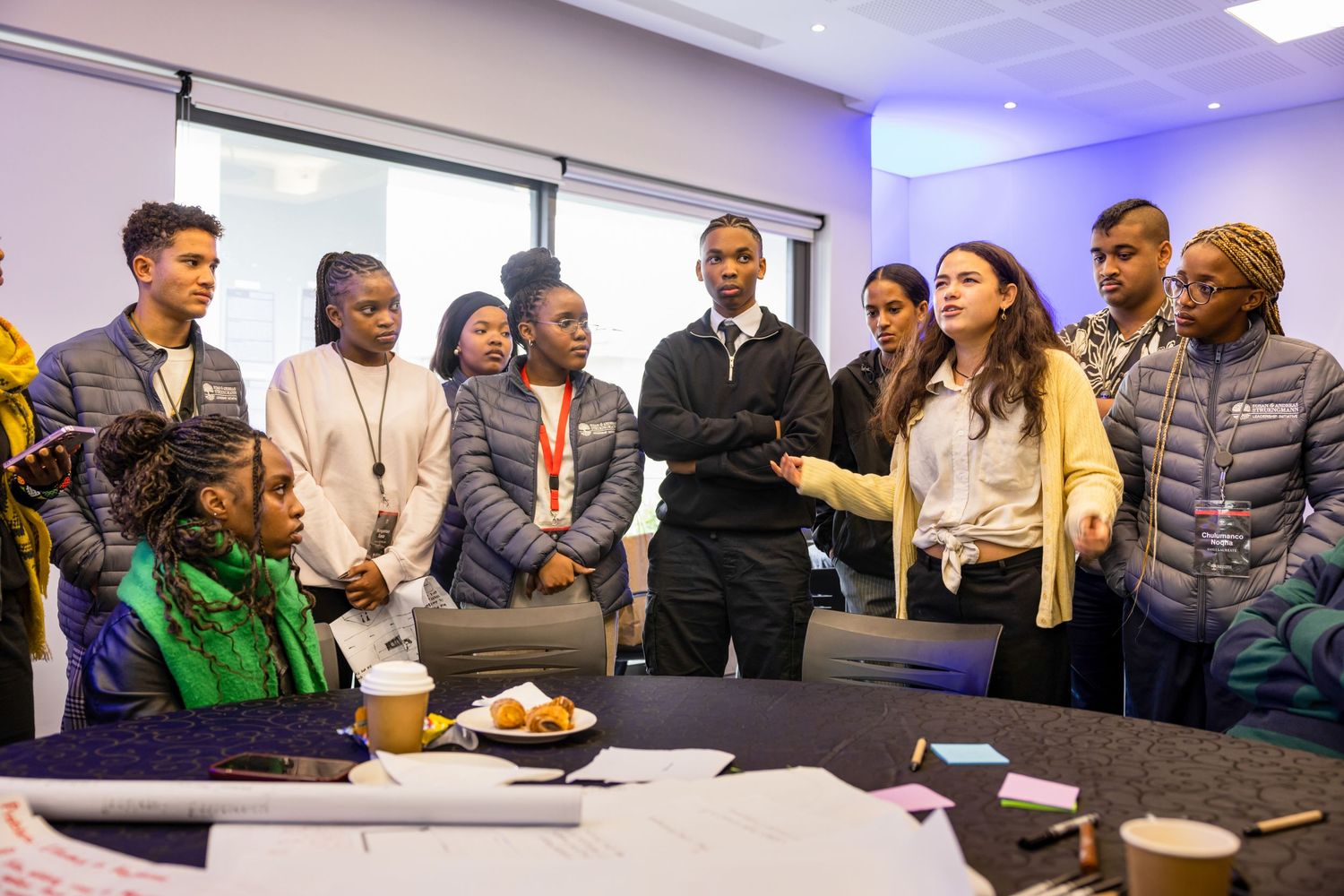 Group discussion in a modern office meeting room with presentation screen visible in background.