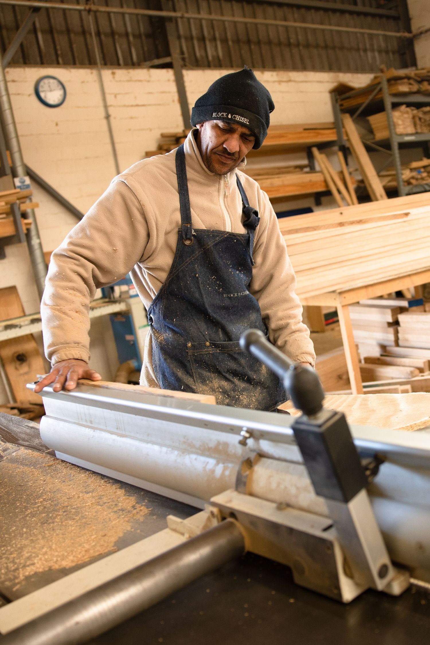 Person wearing winter clothing while working at an industrial cutting station.