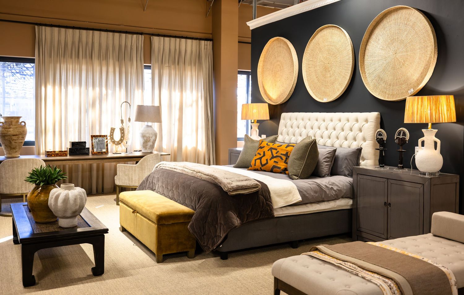 Modern bedroom with circular wall decor, tufted headboard, and mustard yellow accent ottoman.