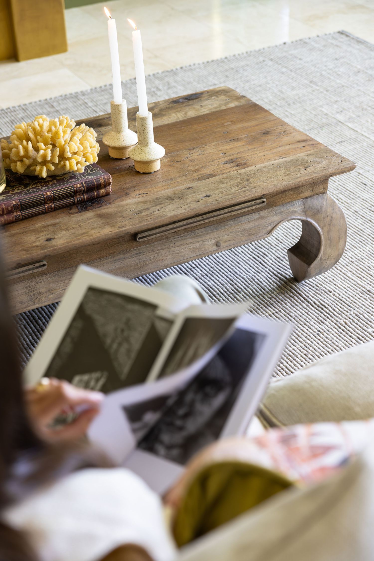 Rustic wooden coffee table with white candles and vintage photographs in casual living room setting.