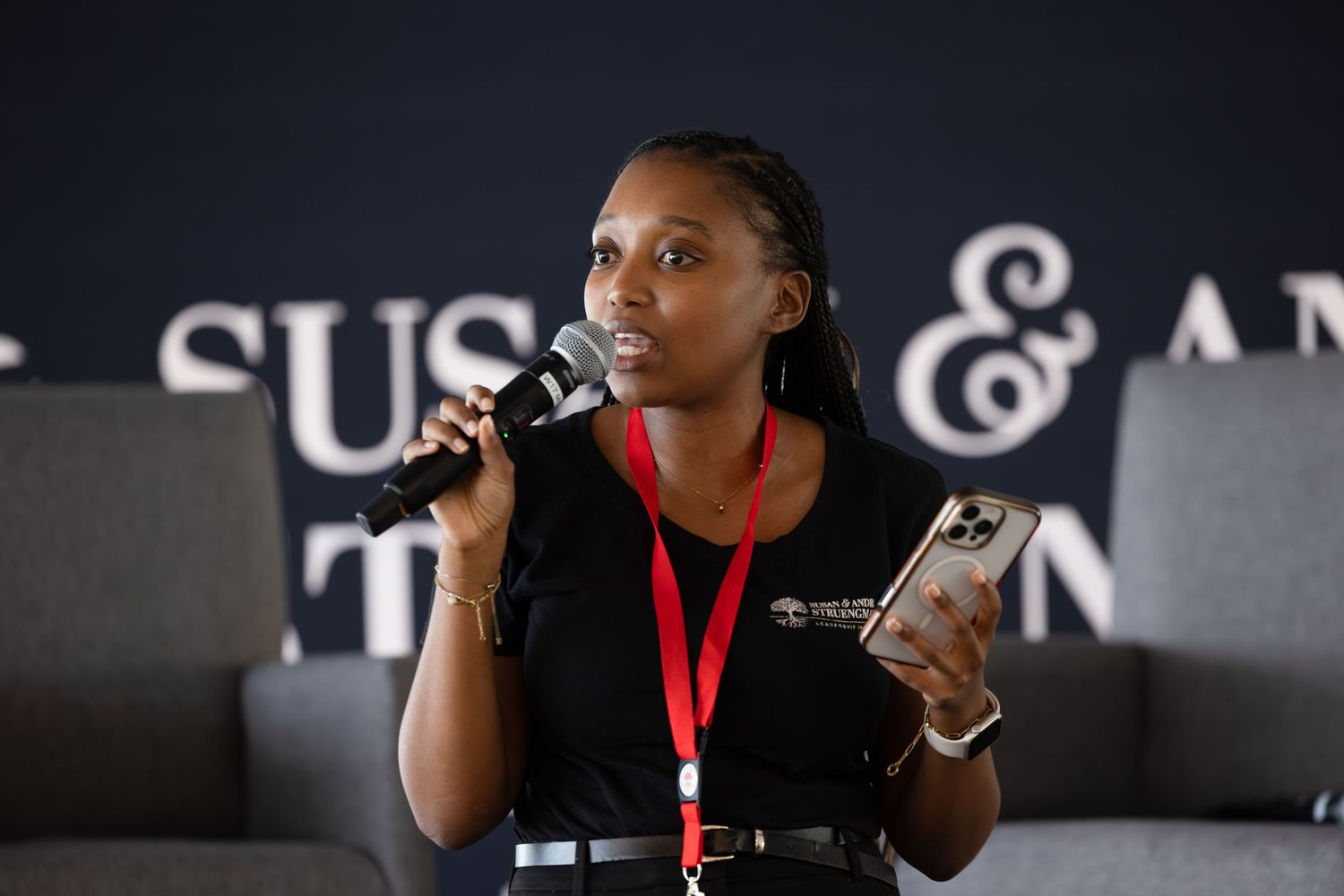 Speaker presents while holding microphone and phone at professional conference.