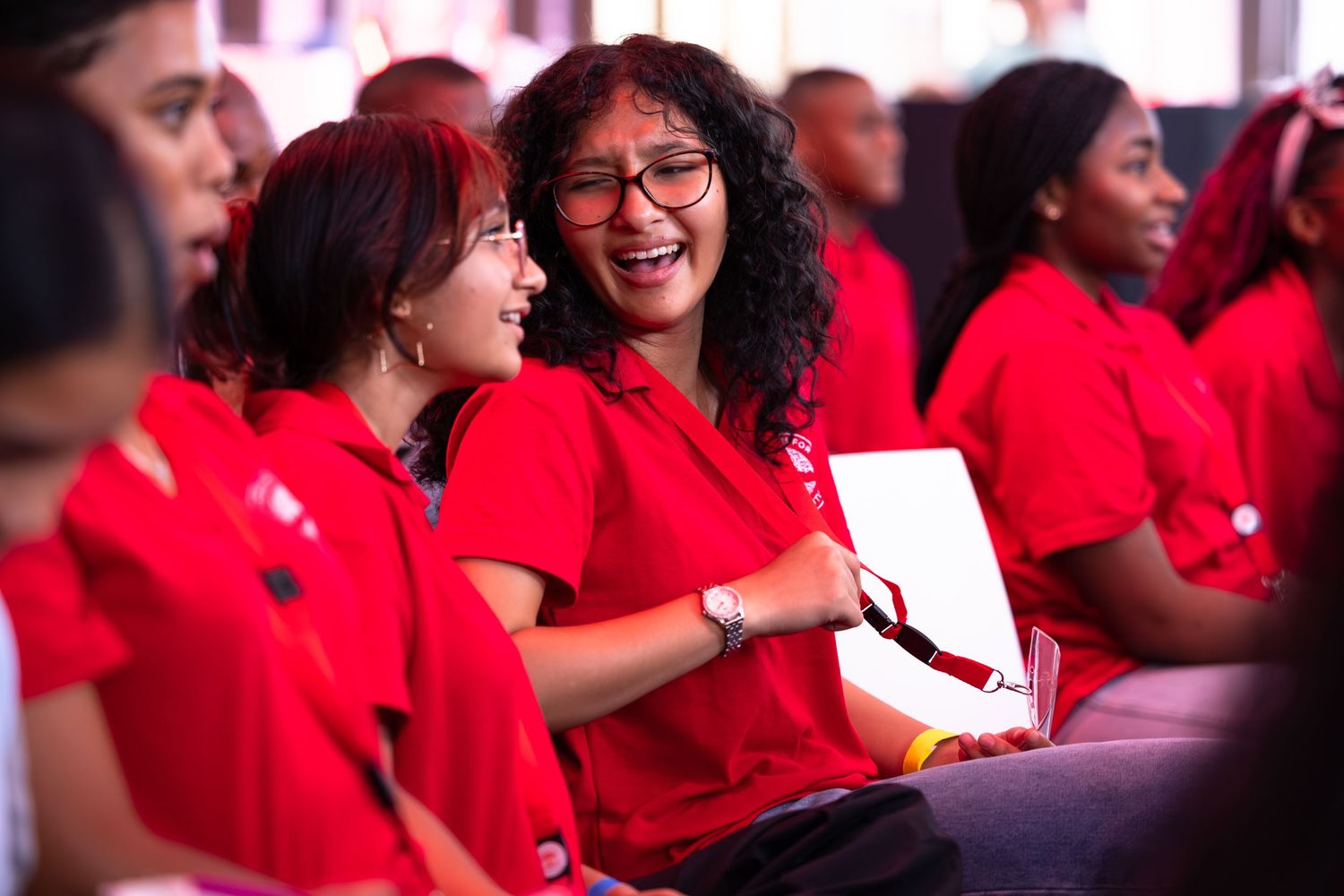 A group of people in red shirts smile and interact during what appears to be a social gathering or event.