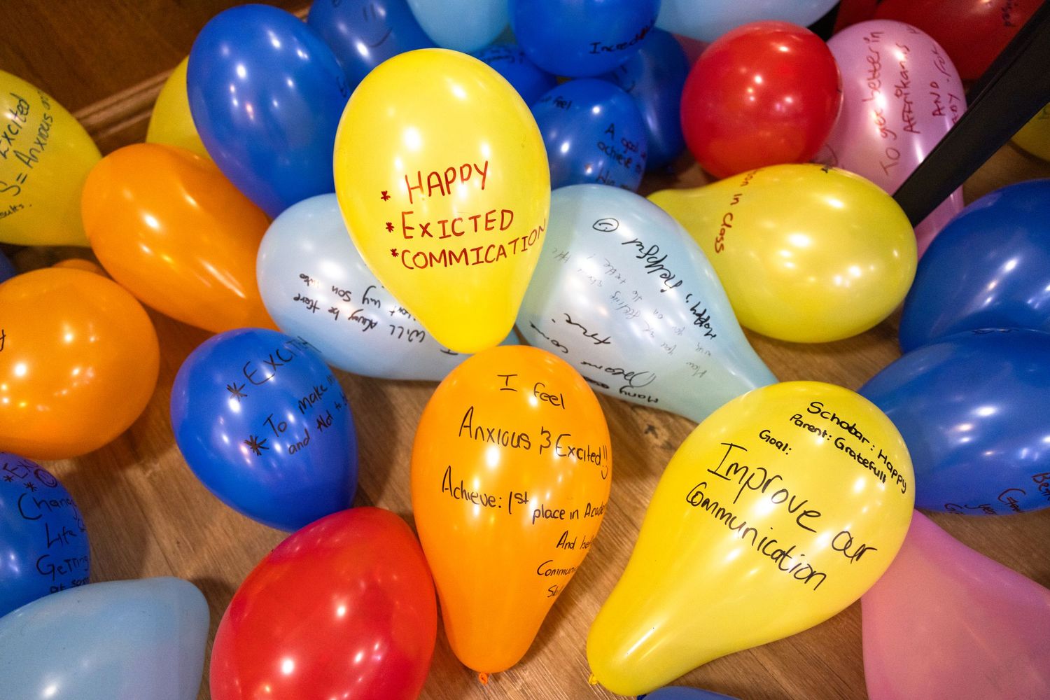 Colorful balloons with handwritten messages decorate a celebration event ceiling.