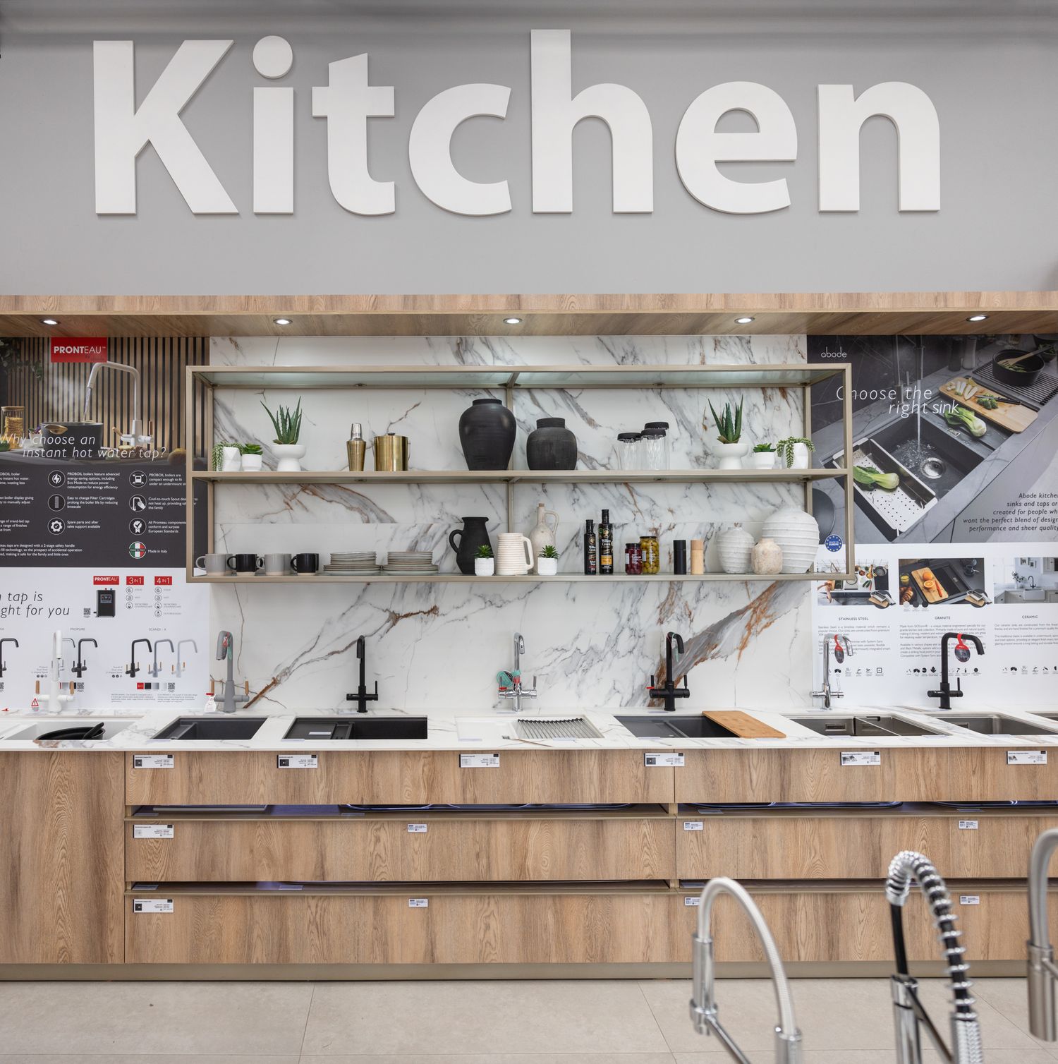 Modern kitchen showroom featuring sleek wooden cabinets and white countertops in a retail space.