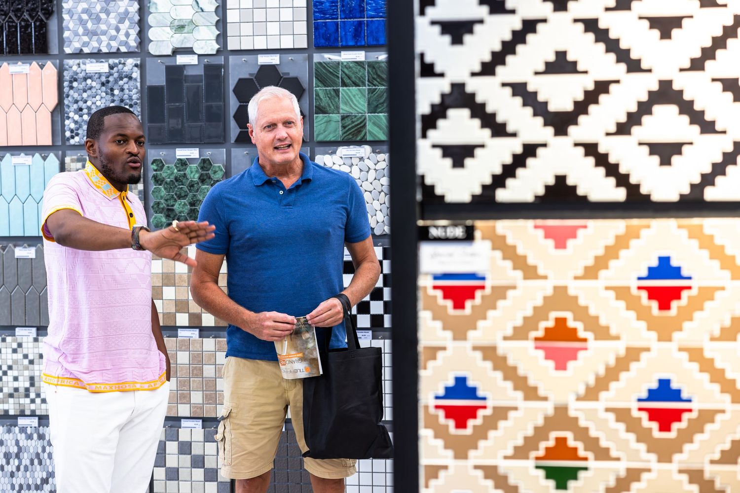 People interacting in front of decorative tile wall with geometric patterns.