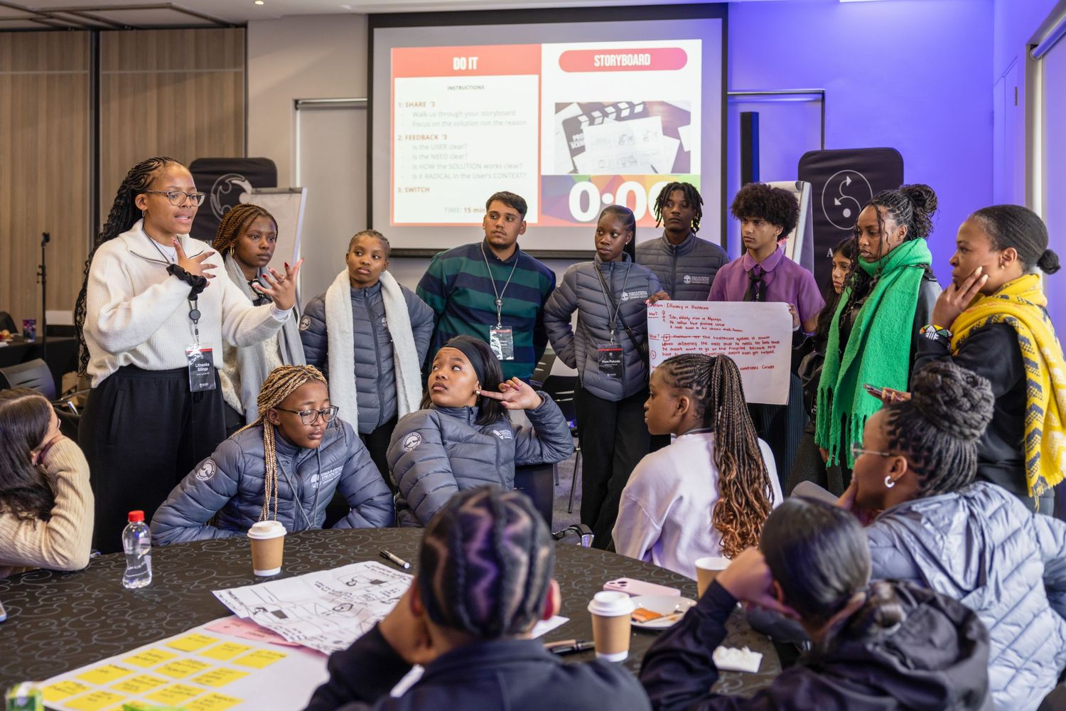 Workshop participants gather around tables reviewing materials during an interactive session.
