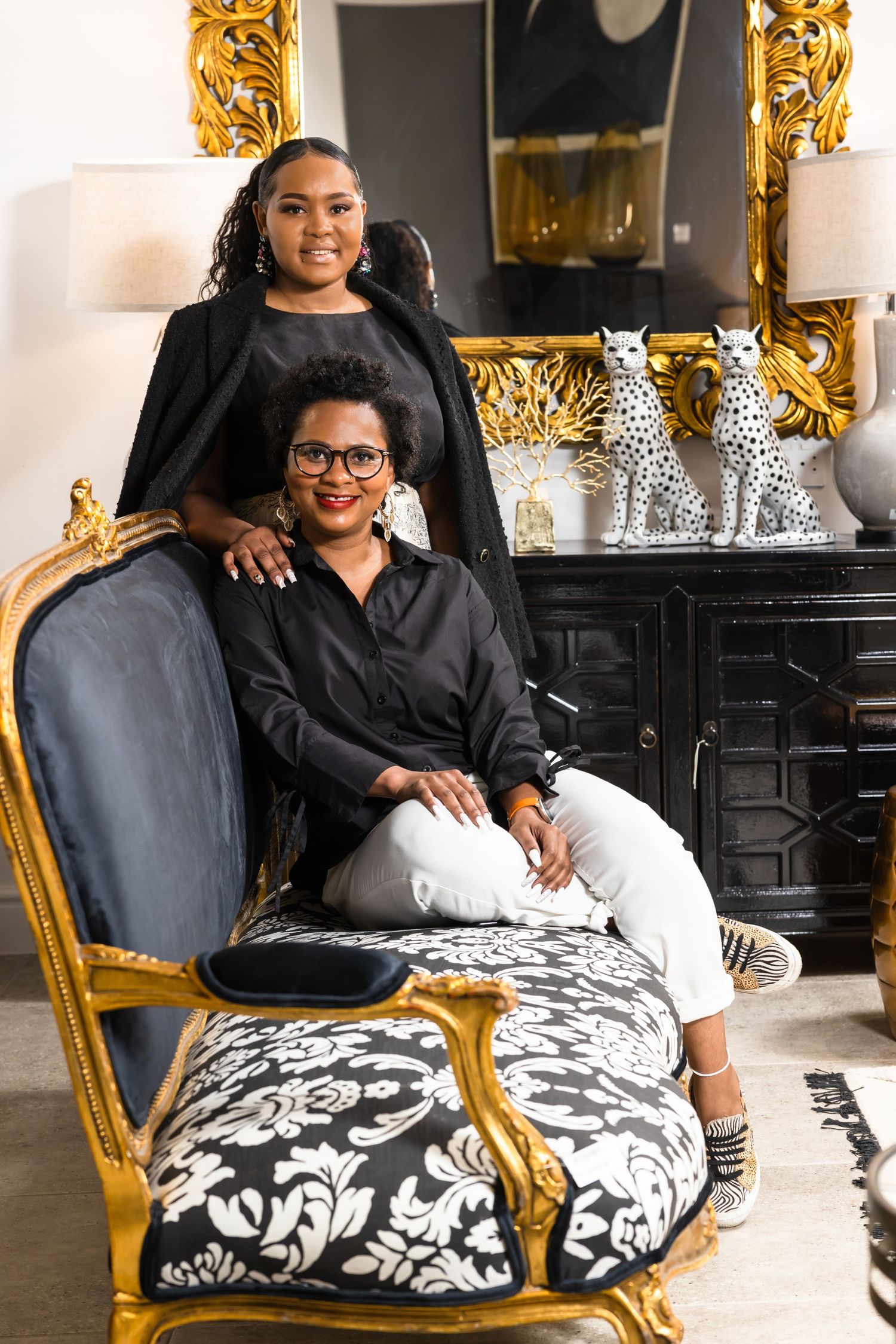 Elegant furniture showroom setting with ornate gold mirror and decorative leopard statues.