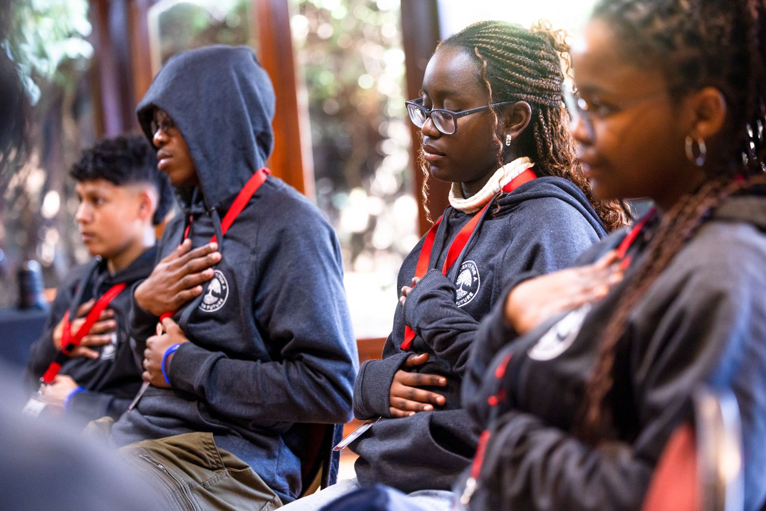 Group of students in hooded sweatshirts gathered outdoors for an event.