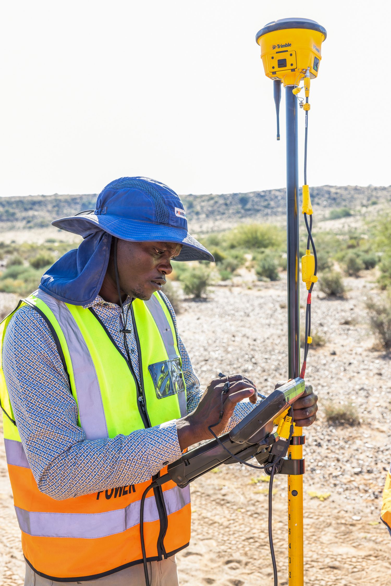 Surveyor operating GPS equipment in arid desert landscape.