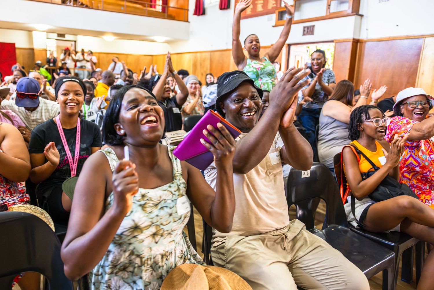 Enthusiastic crowd cheers and celebrates with excitement at an indoor community event.