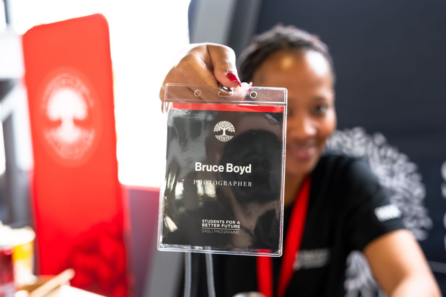Close-up shot of an event badge being displayed against dark background with red signage.