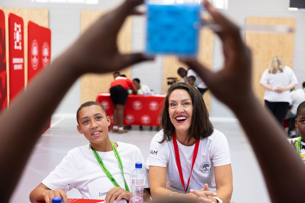 People working together and laughing at a collaborative workspace with red walls and office supplies.