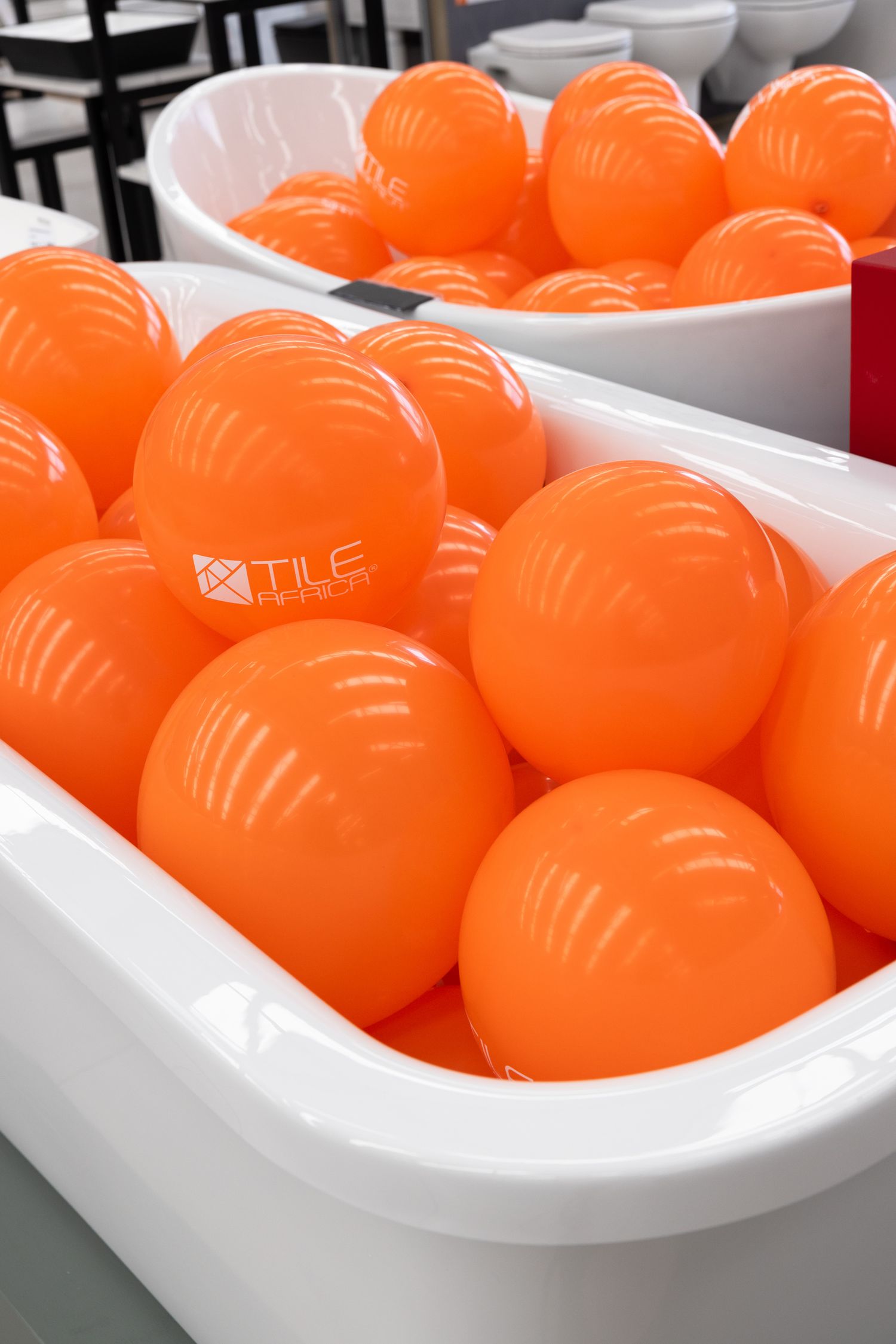 Orange branded stress balls arranged in white display containers.