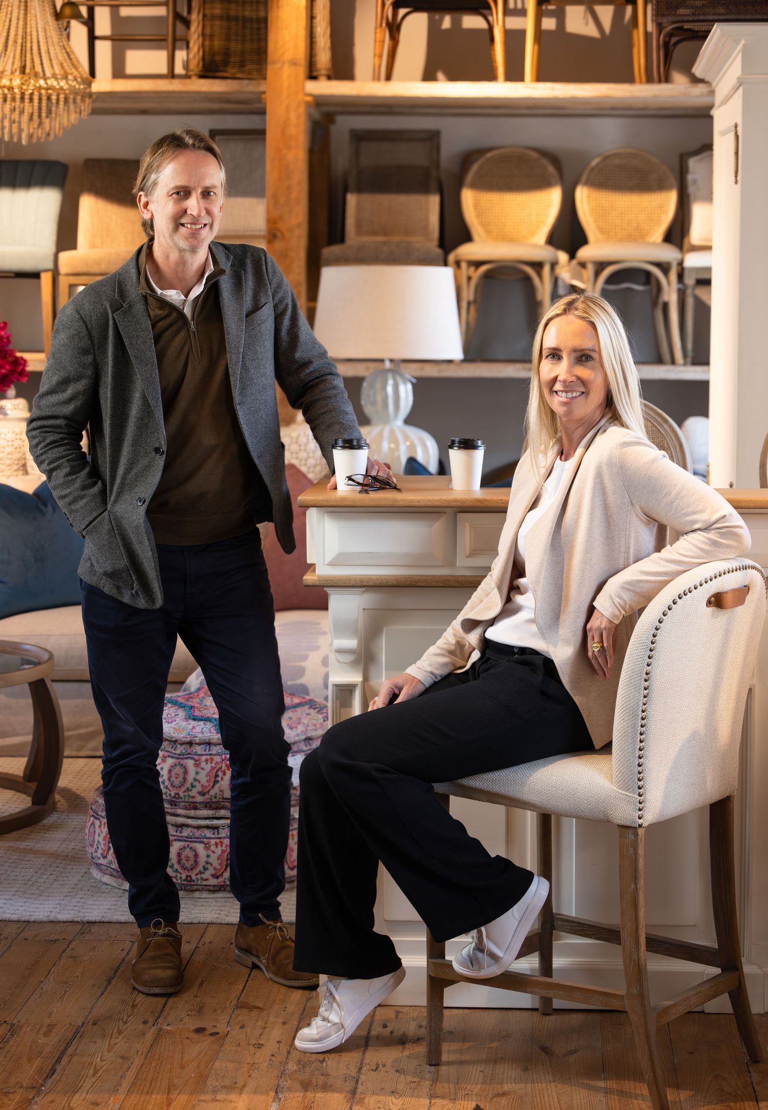 People posing casually in an elegantly furnished room with wooden floors and white chairs.