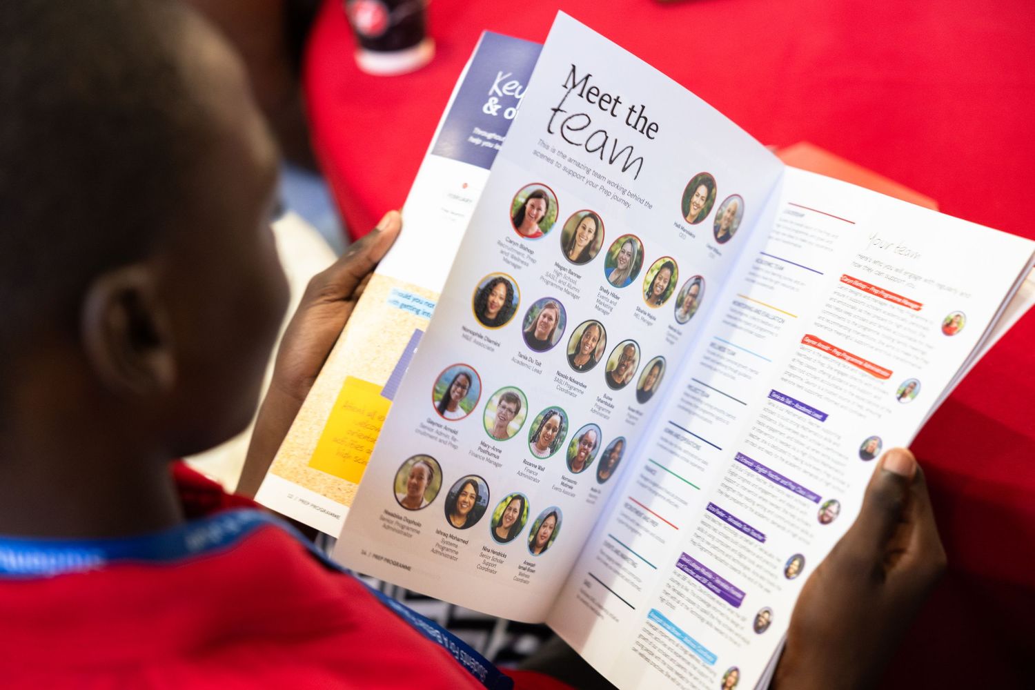 Student reads through a yearbook or school catalog showing small portrait photographs arranged in rows on the pages.