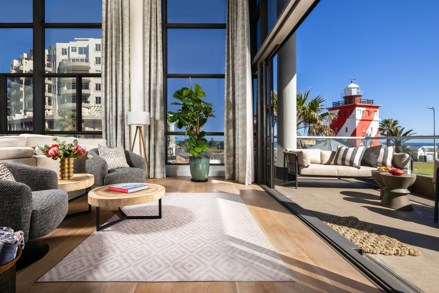 Spacious balcony with floor-to-ceiling windows offering city views and modern outdoor furniture.