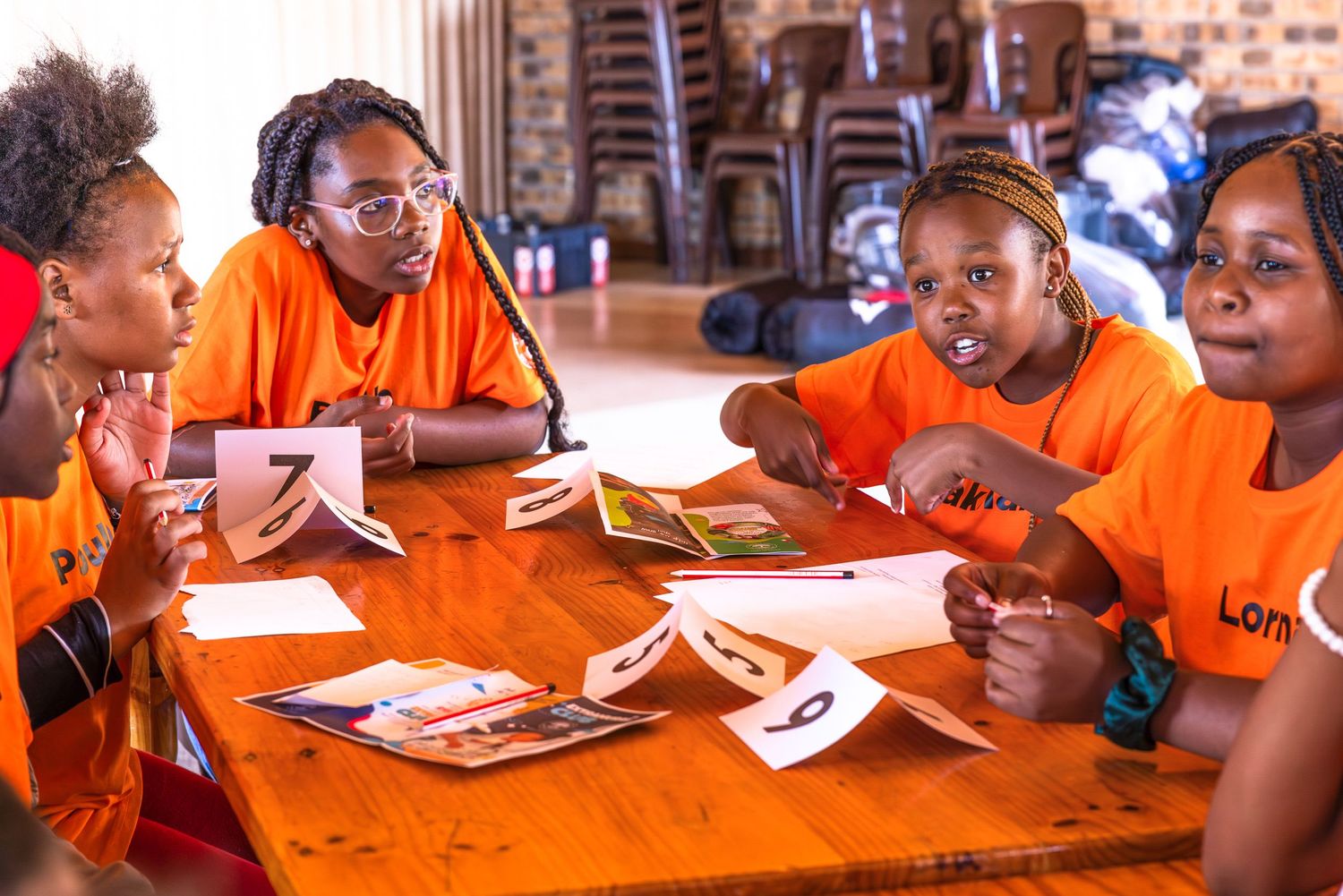 People in orange shirts gathered around tables during a group activity.
