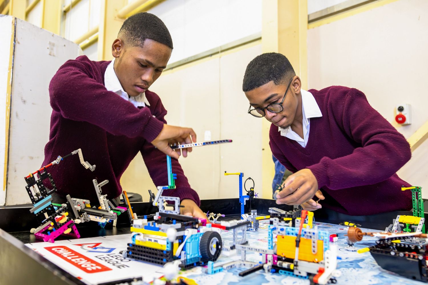 Students work together on robotic components at engineering project table.