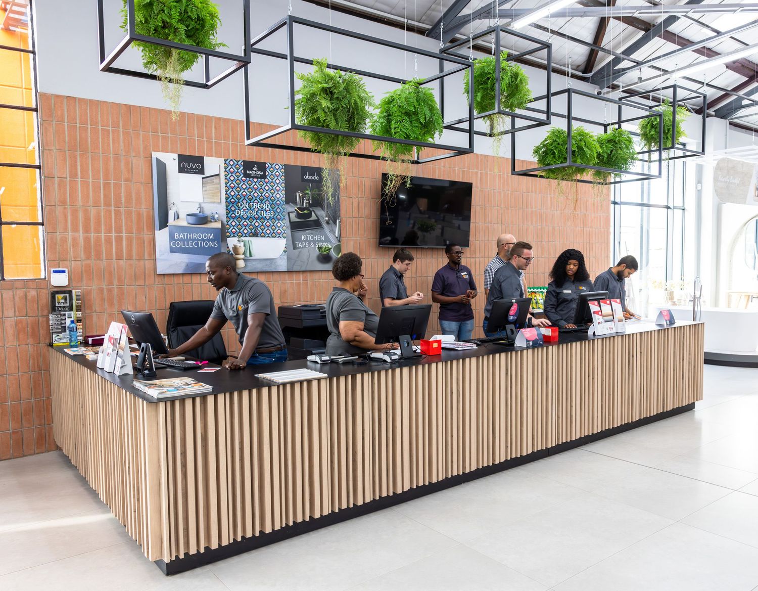 Modern office space with wood slat walls and hanging plants features collaborative seating areas and workstations.