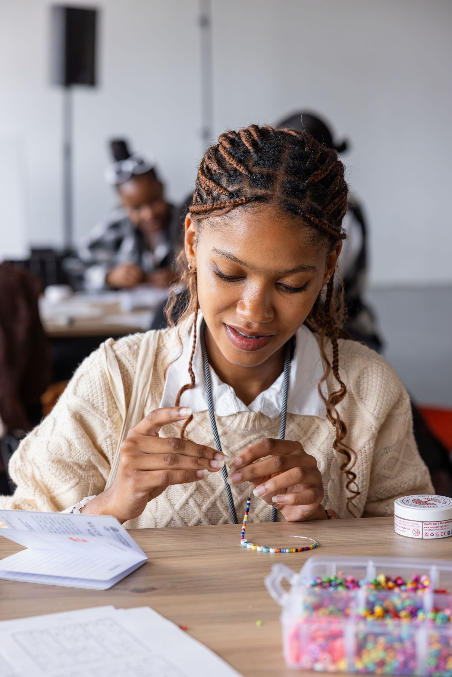 Participant working on a creative project with colorful beads at a desk.