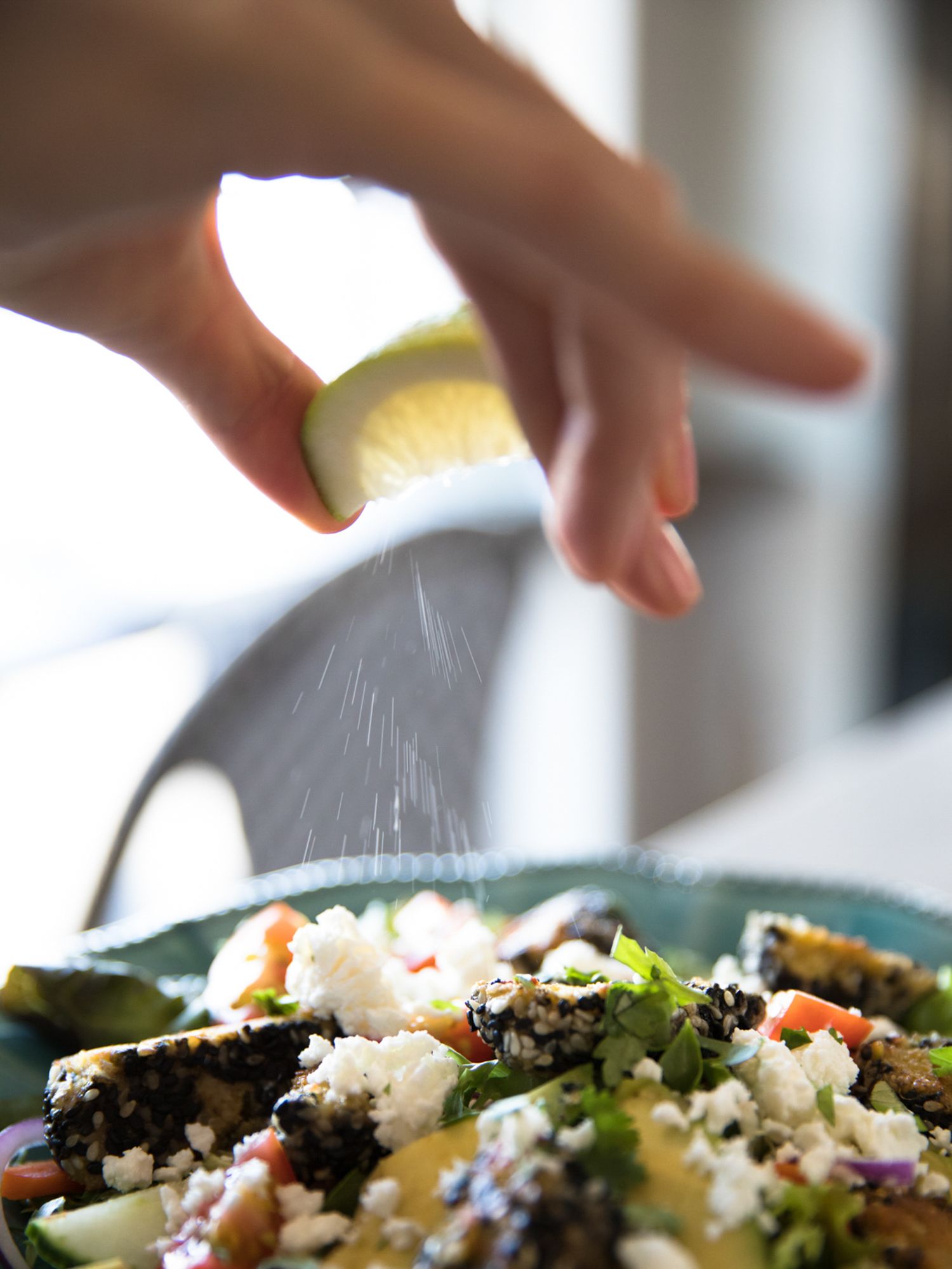 Overhead view of hands eating a fresh salad with feta cheese on a turquoise plate.