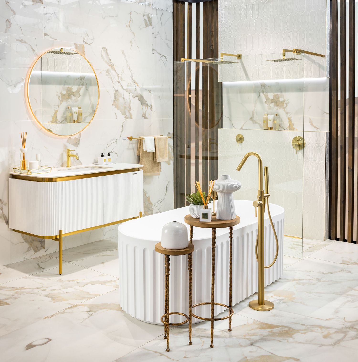 Elegant marble bathroom with white vanity, gold fixtures, and round mirror featuring luxurious design elements.
