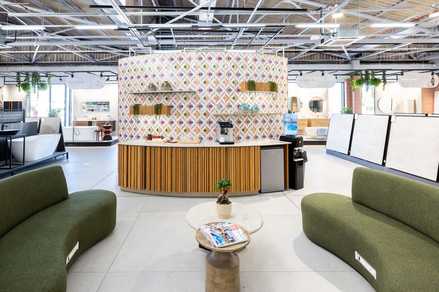 Sleek office lounge area featuring curved green seating and contemporary lighting with geometric wall patterns.