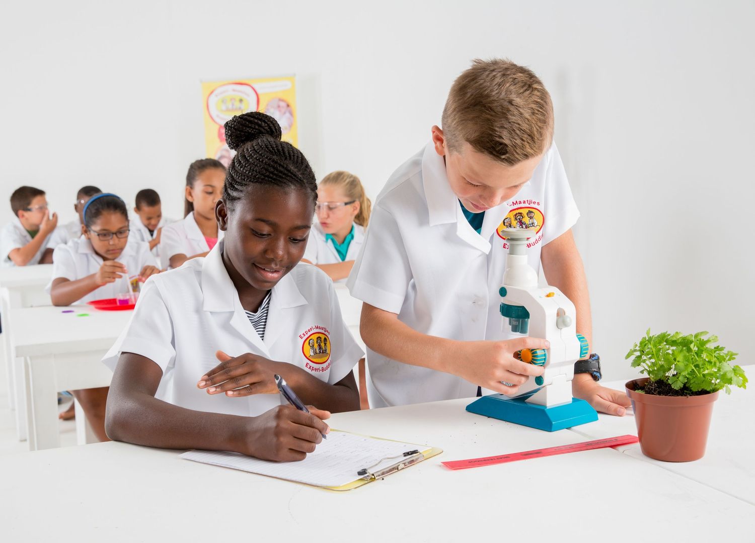 Students collaborate on a science project while wearing white lab coats in a classroom setting.