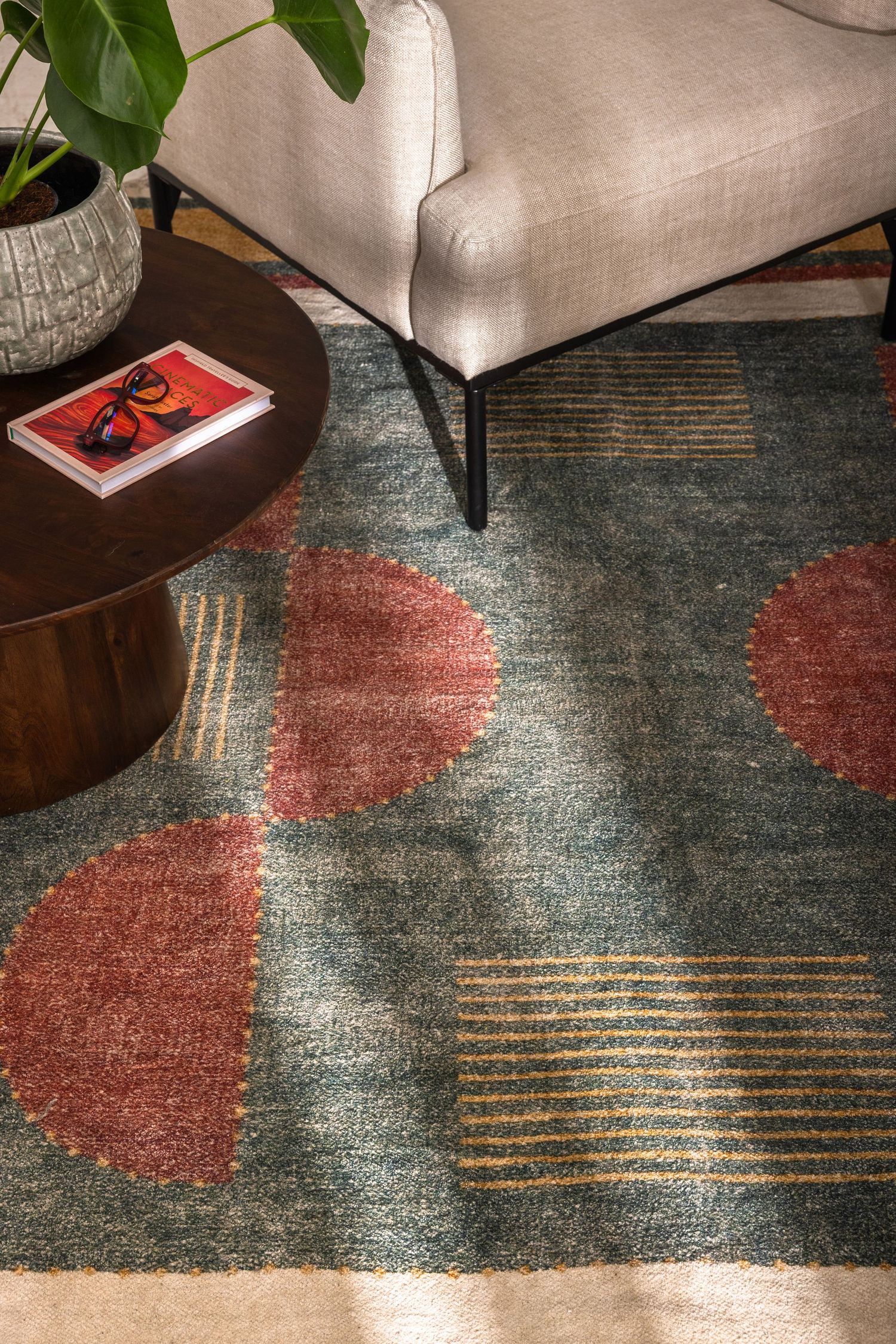 Contemporary area rug with abstract design featuring coral red shapes and metallic gold lines on a teal blue background.