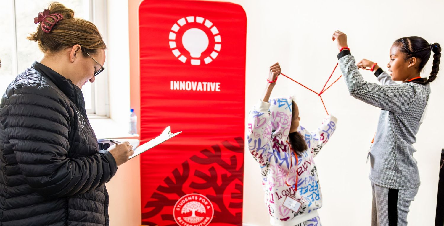 Participants collaborate on an activity near a red display sign during an educational event.