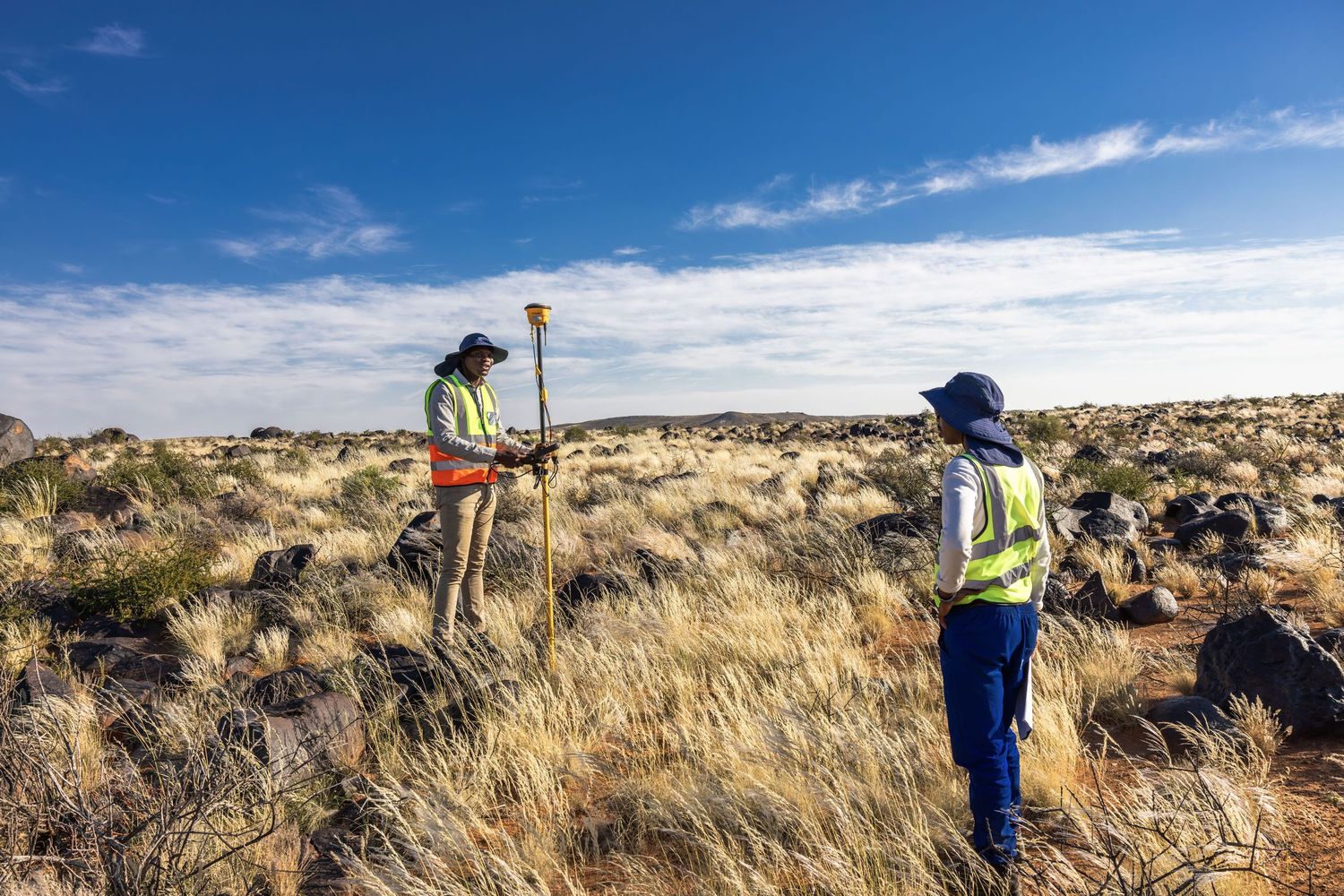 Surveyors using equipment to take measurements in desert terrain.