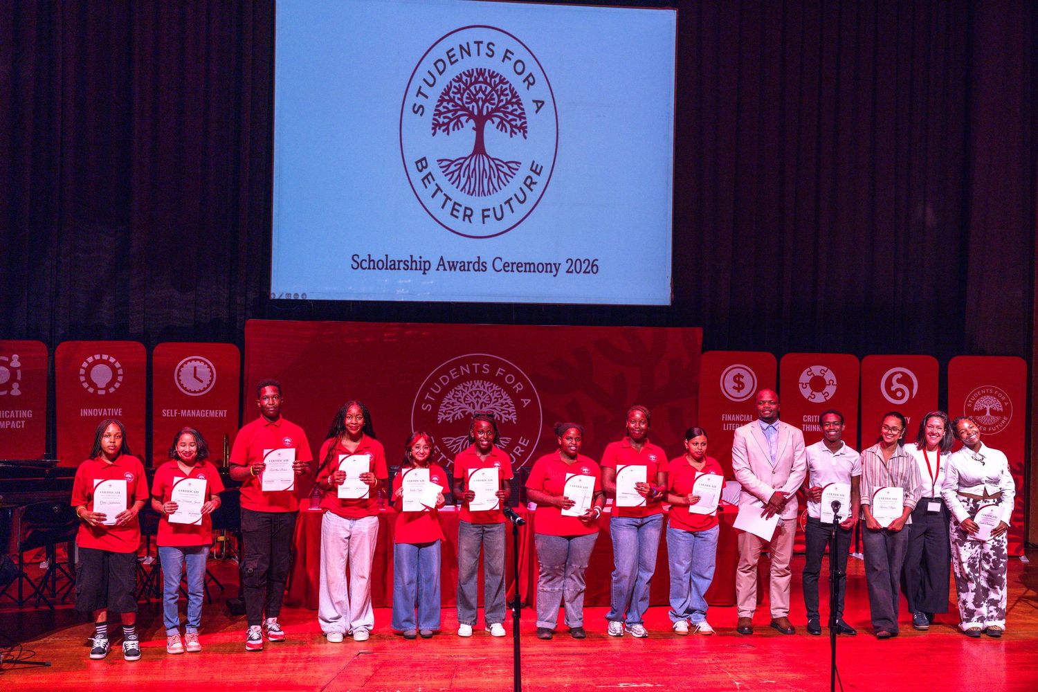 A row of people standing on stage during what appears to be a graduation or awards ceremony.