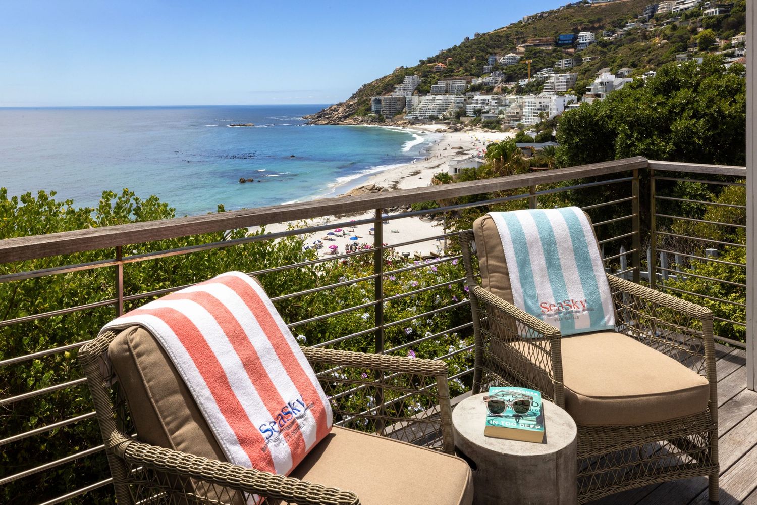 Oceanfront terrace with striped cushioned loungers and panoramic views of a pristine beach and turquoise waters.