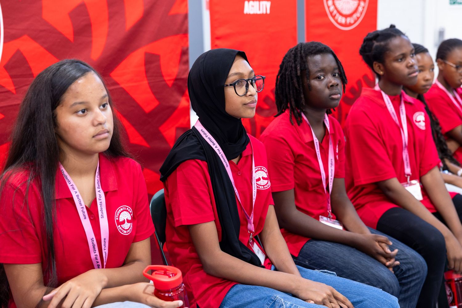 Group wearing matching red shirts seated together at an event.