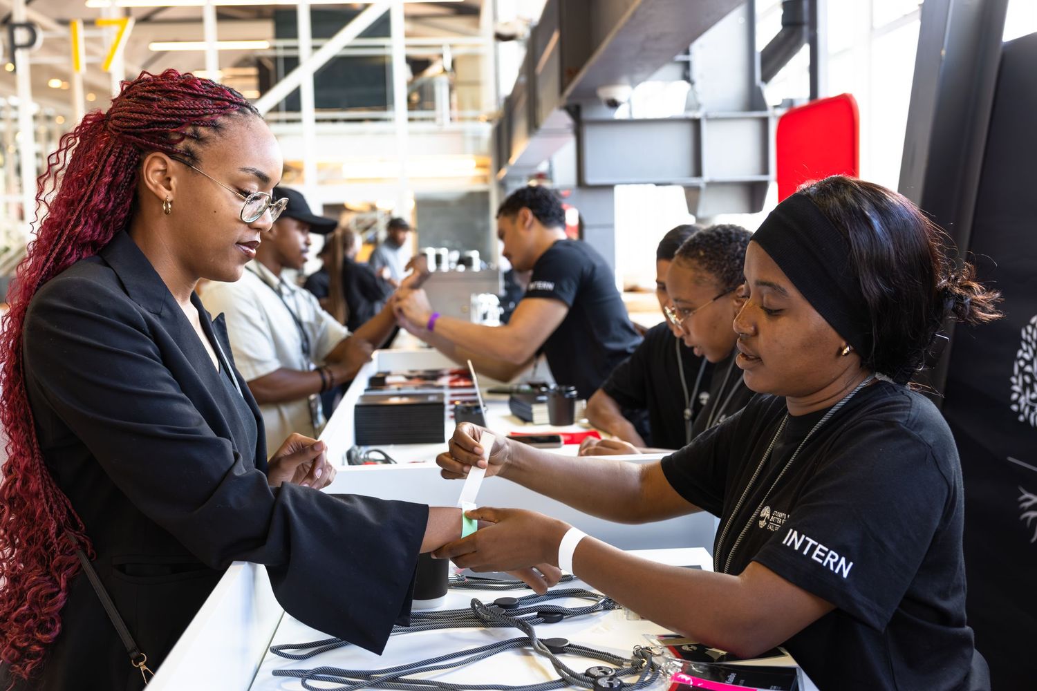 Event staff members assist attendees at registration desk during professional conference.