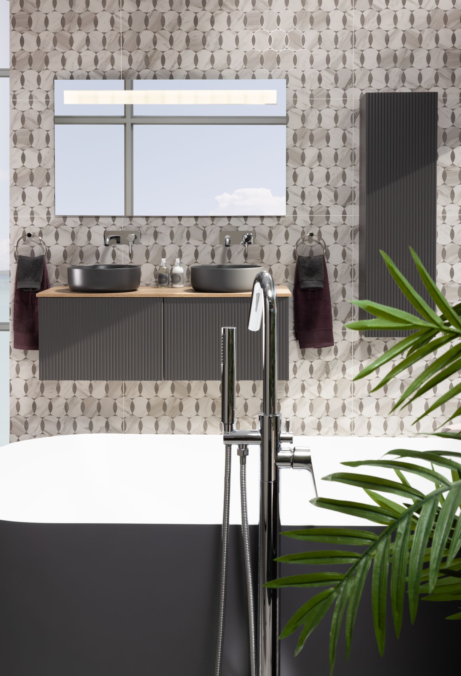 Elegant bathroom with patterned wallpaper, floating vanity, and black freestanding tub accented with tropical plants.