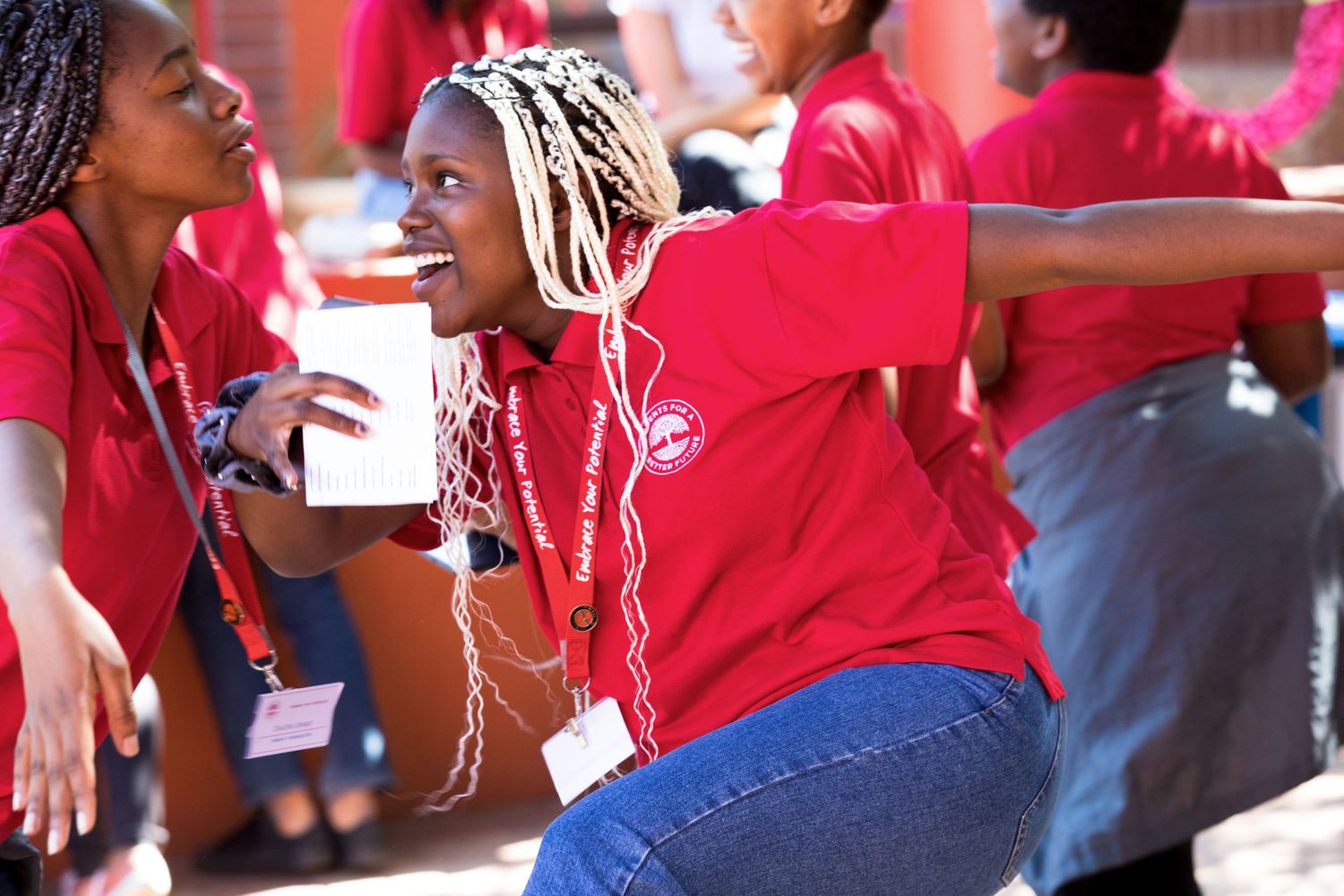 Students in matching red shirts share an animated conversation.