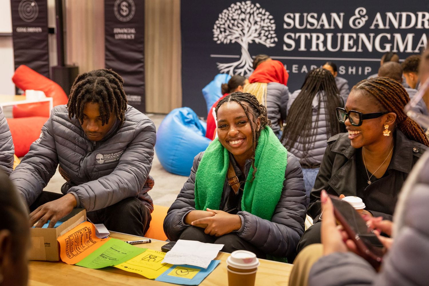 Workshop participants gather around tables with branded signage visible in background.