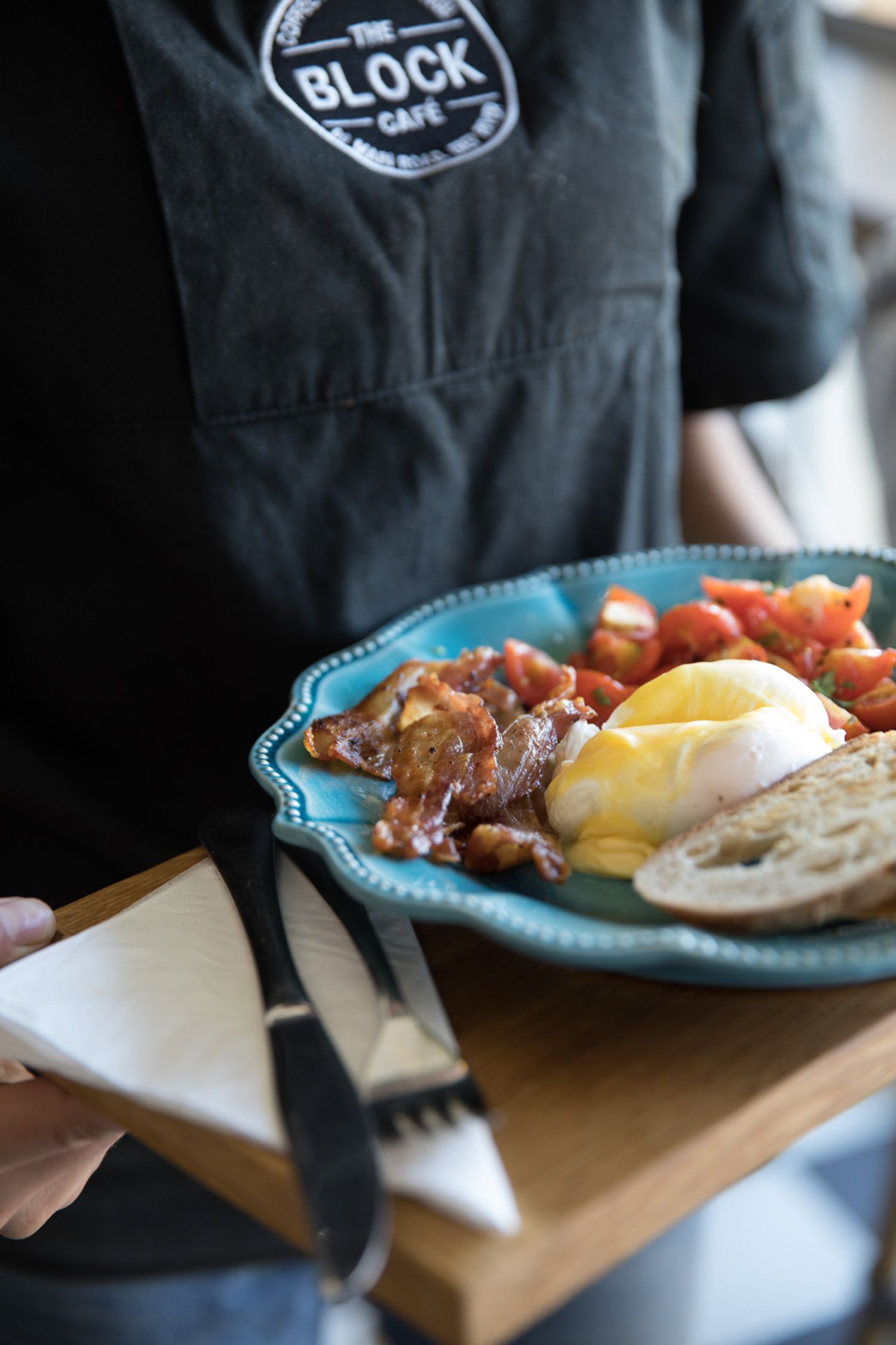 Plated breakfast dish with eggs and bacon served on a turquoise ceramic plate.