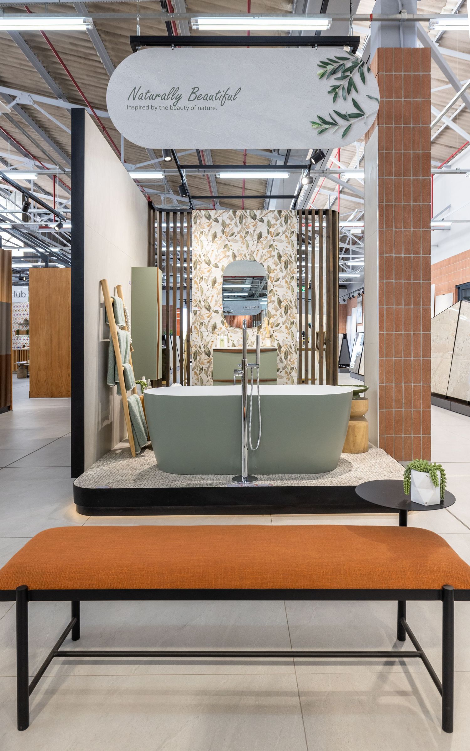 Modern retail display with green bathtub and stone accent wall showcasing bathroom fixtures in a minimalist showroom setting.