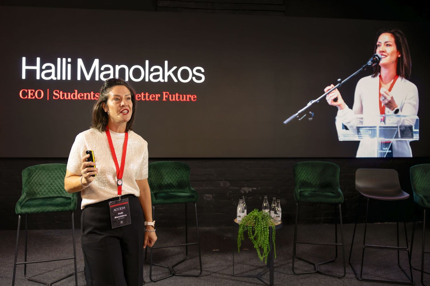Professional presentation stage with speaker name and title displayed on screen.